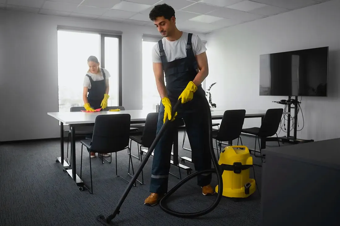 Reinigungskräfte bei der Arbeit in einem Besprechungsraum.